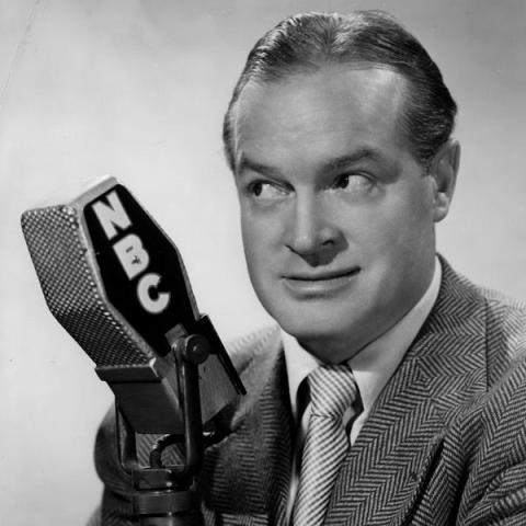 Black and white image of Bob Hope with a NBC microphone. 