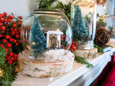 A Christmas snow globe sits upon a fireplace mantel.