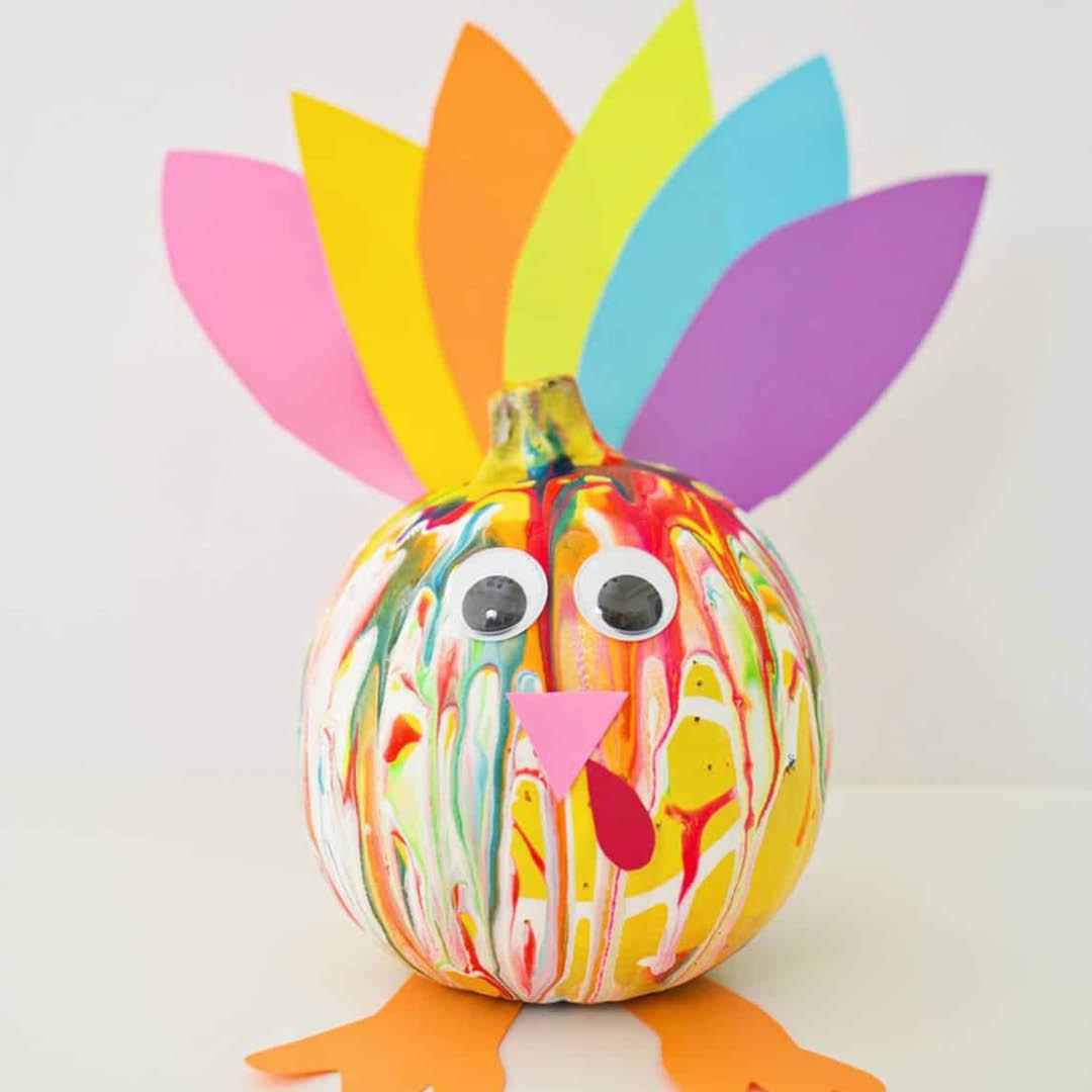 painted pumpkin with colorful paper turkey feathers